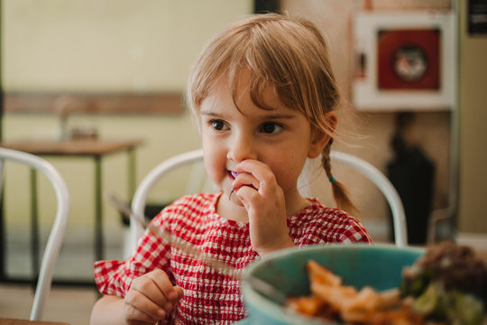 Appetizing fragrant assorted food in blue bowl and adorable girl eating at table