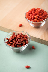 Frische und getrocknete Goji-Beeren Superfood in Glas Schale auf Holz Brett und Mint Grün Pastell Hintergrund