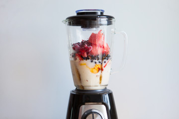 A blender filled with fresh whole fruits for making a smoothie or juice. Healthy eating concept. - 278878480