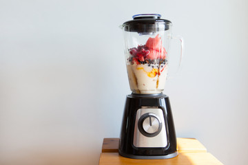 A blender filled with fresh whole fruits for making a smoothie or juice. Healthy eating concept. - 278878493