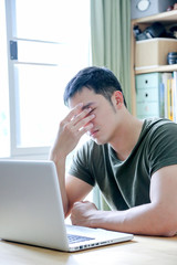 young asian wearing a green tshirt working with laptop in home office