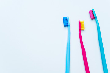 Colorful tooth brushes with bright color bristles on a light pastel blue background. Dental tools with empty space for text for  your mockup.