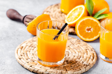 Orange juice in glass with fruits on grey  background, copy space.