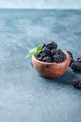 Blackberries in wooden bowl  on dark blue background.