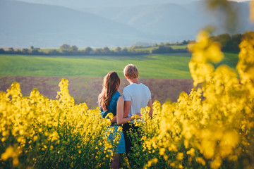 Fototapeta premium young couple in summer flower field with yellow flowers, rapeseed flower field in spring Germany