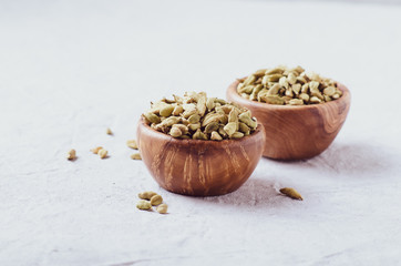 Dried green cardamon seeds spice in a wooden bowl