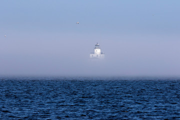 The thick fog partially obscures the lighthouse on Lake Michigan