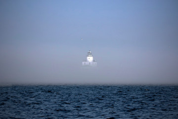 The thick fog partially obscures the lighthouse on Lake Michigan