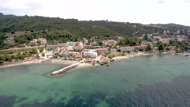 Aerial view of small  beach with rocks under a tourist village in the area of Agia Paraskevi Halkidiki, Greece ,sideways movement by drone