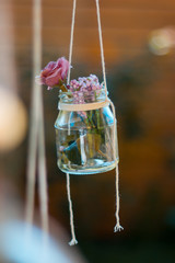 Decoration glass jar with flowers hanging with blur garden background. Soft focus