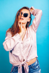 young pretty girl in sunglasses posing happy smiling on blue background, lifestyle people on summer vacation concept