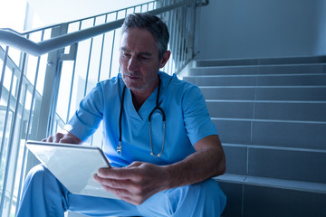Male doctor using digital tablet on staircase in the hospital