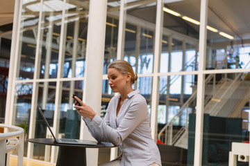 Businesswoman using mobile phone in the corridor at office
