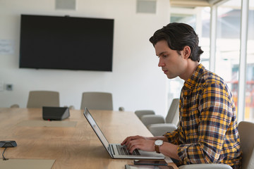 Male executive using laptop in the conference room at office