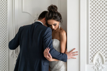 groom passionately embraces bride and hugs him against wall. Hot love at newlyweds. Feelings and relationships in young family.