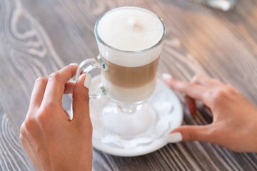 girl holds glass latte coffee in hands. Three Layer Latte