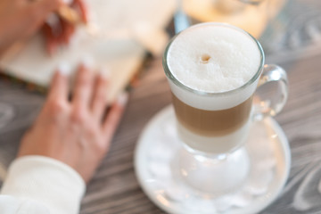 girl draws heart in notebook, next to coffee is latte and candle burns. concept of love coffee, home warmth and comfort.