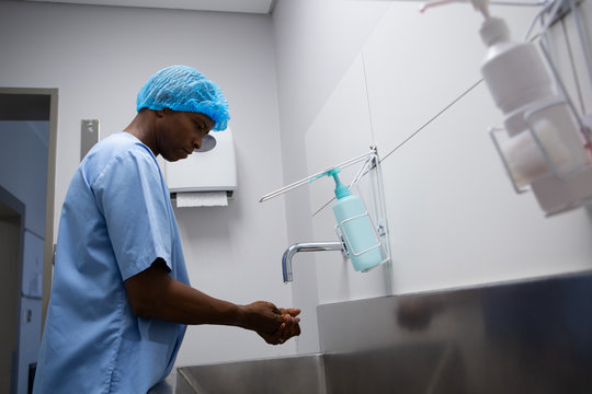 Male Surgeon Washing Hands In Sink At Hospital