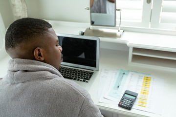 Man looking at bills on desk in bedroom at comfortable home