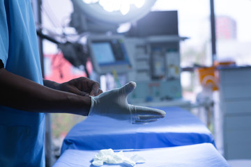 Male surgeon wearing surgical gloves in operating room of hospital