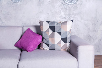gray sofa with purple pillows in a room with a gray wall