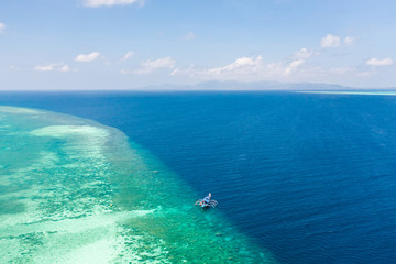Fototapeta na wymiar Large coral reef, top view. Tourist boat near the atoll. Seascape in the Philippines in sunny weather.
