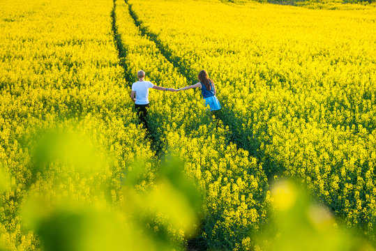 Beauty Family Man And Woman Walk And See To Yellow Canola Field In Summer