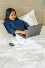 Woman sitting on bed and working on laptop