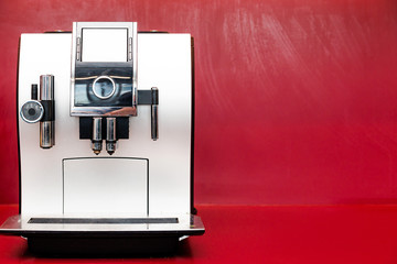 coffee machine stands against a red wall