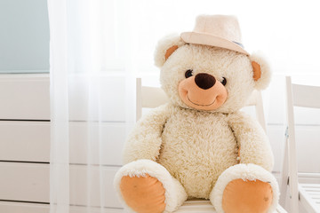 Teddy bear is sitting on the chair and smiling at the camera