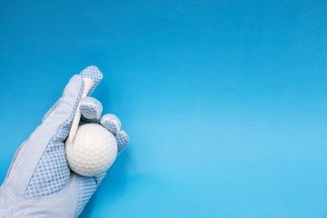 Hand in blue golf ball is holding white golf ball is on on blue sky background.