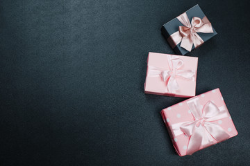 beautiful gift boxes wrapped in paper with red, gold and pink ribbon on a black surface. Top view...