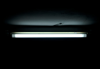 An ominous neon light inside a basement. Scary horror close-up detail.