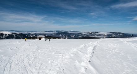 Fototapeta na wymiar winter mountain panorama with many hills, few hikers and blue sky with clouds from Praded hill in Jeseniky mountains in Czech republic