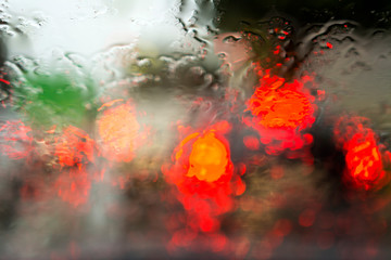 Fototapeta na wymiar Blur on wet glass. View through the glass of the car on the lights of cars in the rain