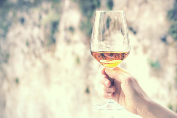 woman hand holding a wine glass, rusty background with copy space (vintage effect picture)