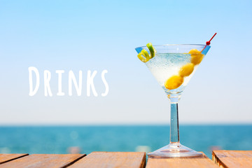 Glass of martini bianco at the wooden pier. Concept of summer vacation. Popular cocktail by the sea. Vacation background. Horizontal. Drinks wording