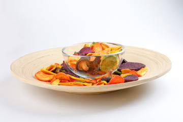 Healthy vegetable chips yellow sweet potato purple sweet potato carrot green radish green beans and shiitake mushrooms in glass bowl wooden plate