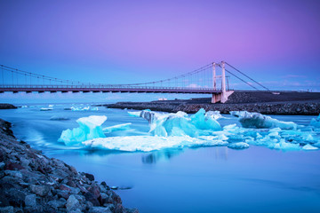 Fototapeta premium Iceberg parts float to the ocean under a bridge in the bay in the famous Jokulsarlon ice lagoon in Iceland. (global warming, greenhouse effect - concept)