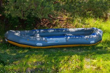 In the shade under the trees large inflatable rafting boat near the river in the Altai Mountains....