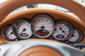 Dashboard is covered in beige genuine leather of a sports car with instruments speedometer and...