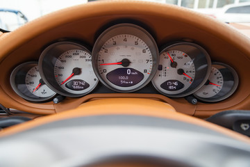 Dashboard is covered in beige genuine leather of a sports car with instruments speedometer and...