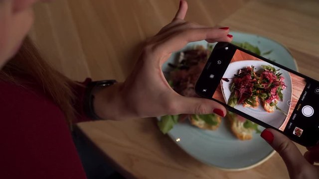 Closeup of Young Woman Taking Photo Of Food With Phone in Restaurant 4K. Female Taking Pictures of Croissant with Prosciutto.