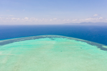 Atoll and blue sea, view from above. Seascape by day. Turquoise and blue sea water.