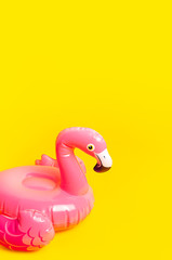 Creative summer beach concept. Inflatable pink mini flamingo on yellow background, pool float party. Flat lay, copy space. Flamingo Trend Inflatable Toy. Summer background. Layout for design