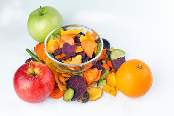 Healthy vegetable chips yellow sweet potato purple sweet potato carrot green radish green beans and shiitake mushrooms in glass bowl apple orange fruit
