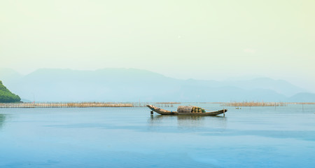 Fototapeta na wymiar Lonely wooden fishing boat on the lagoon looking forward to going to the sea as a wish for people to look forward to good things in the vast sea