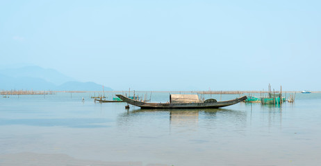 Fototapeta na wymiar Lonely wooden fishing boat on the lagoon looking forward to going to the sea as a wish for people to look forward to good things in the vast sea