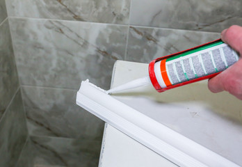 Man is putting glue on gypsum baseboard. Maintenance repair works renovation in the flat ....