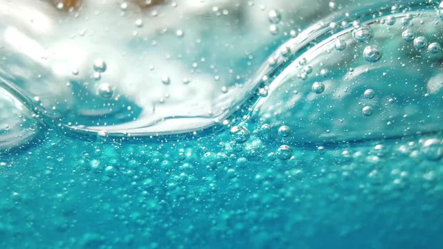 Blue liquid background, bubbles move gently within glass container